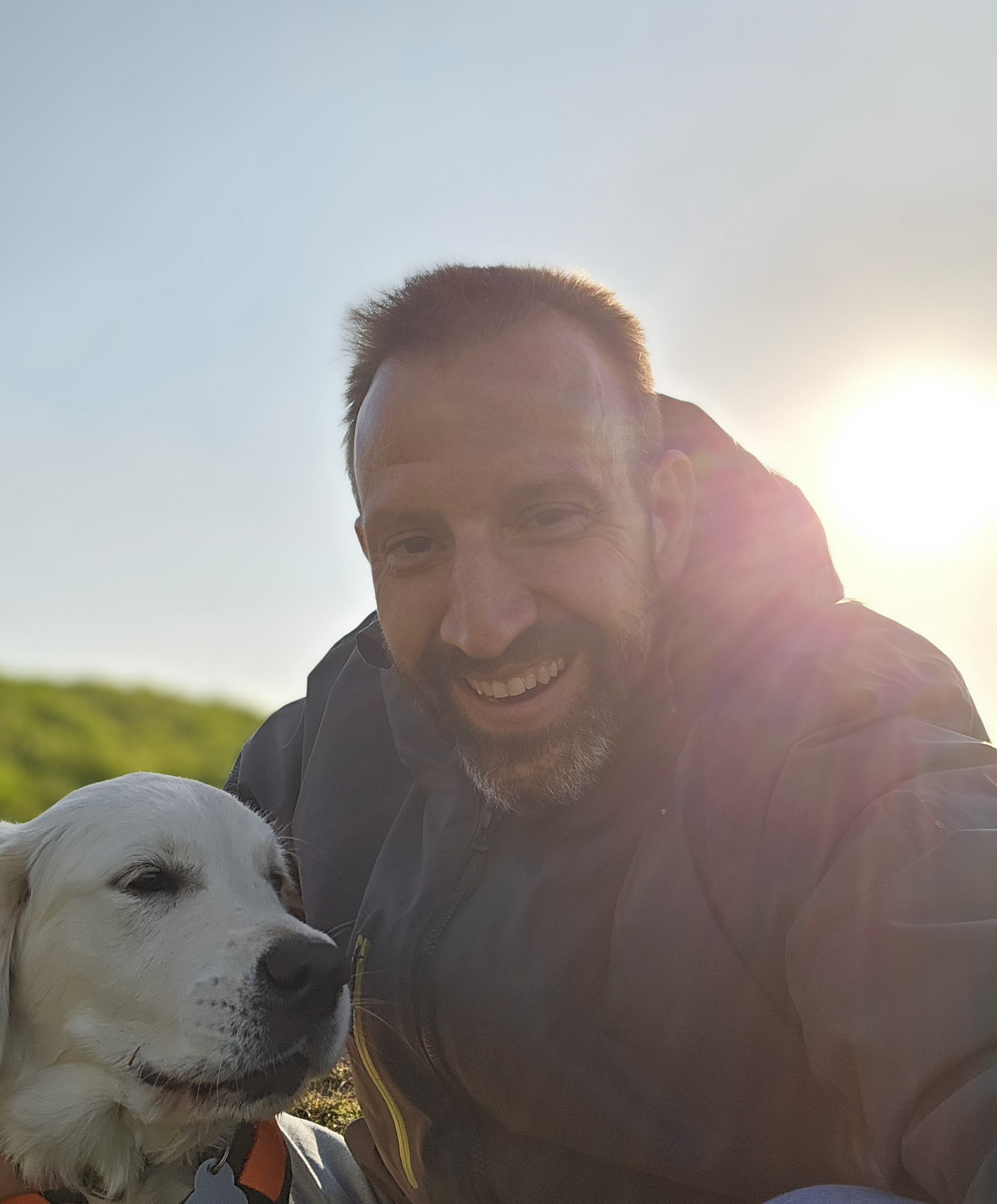 Rifat Radjeb neben seinem Golden Retriever vor einem Sonnenuntergang - Sinnbild von Verbindung und Vertrauen